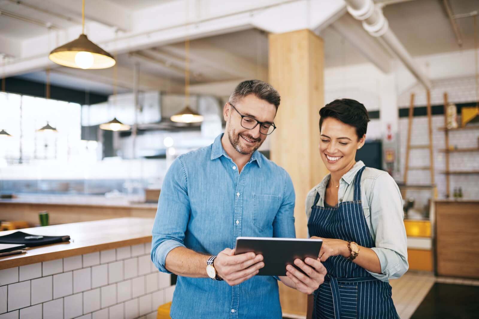 Un gerente de restaurante y una camarera revisando reseñas de Google juntos en una tablet